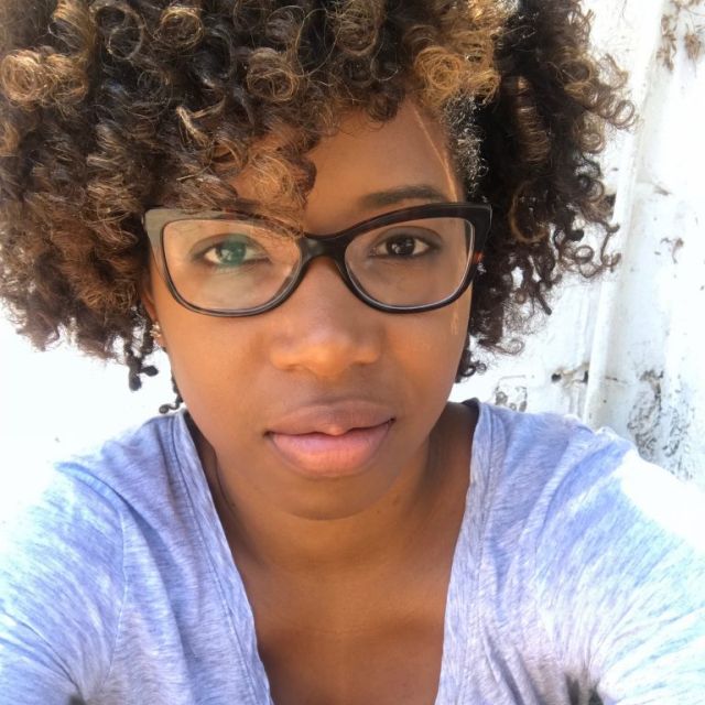 Selfie portrait of Patrese in a light top, looking serious at the camera.