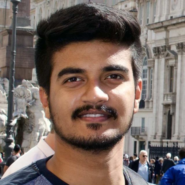 Portrait of Pratyush smiling in front of a cityscape.