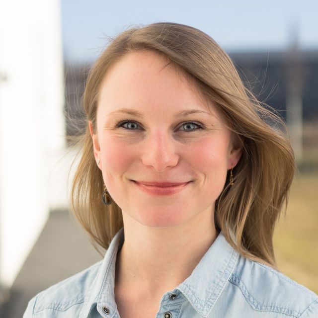 Catharina in a light blue top, smiles at the camera while outside.