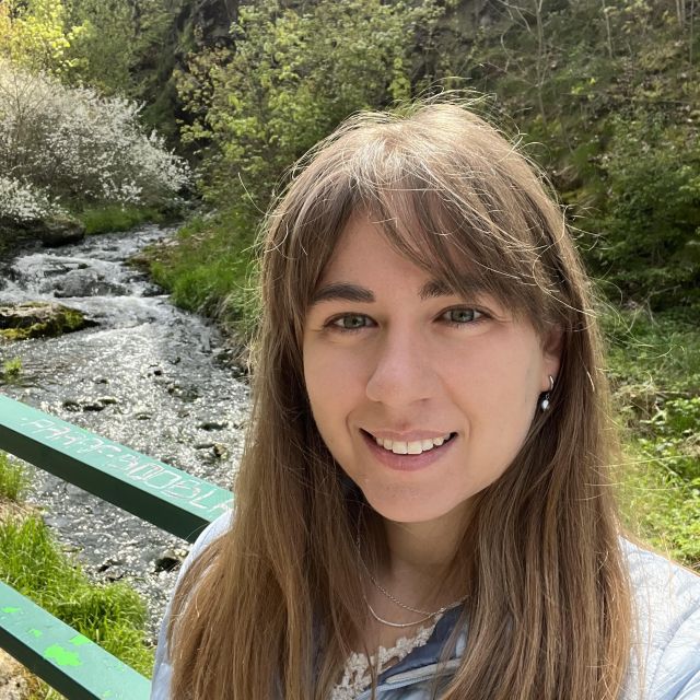 Rachel stands on a bridge over a small stream.