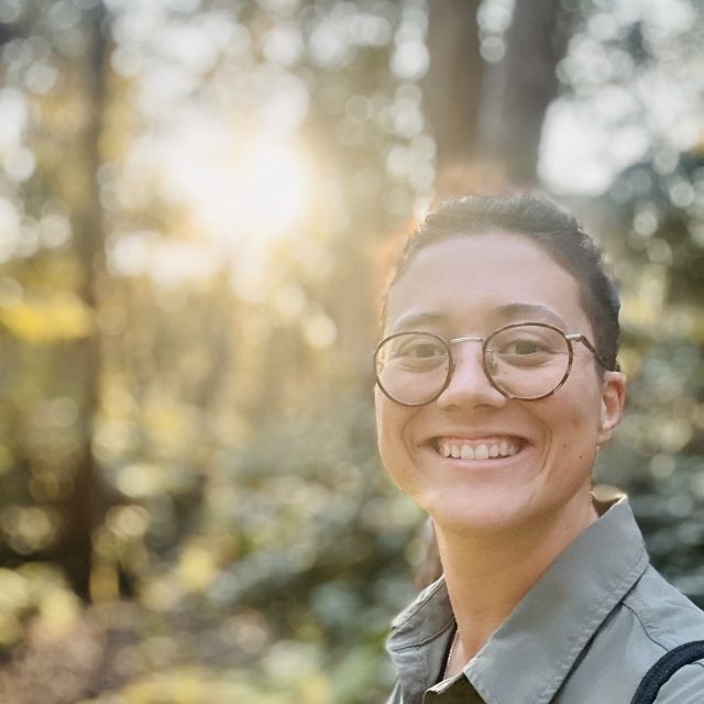 Lívia smiling at the camera in a forest.